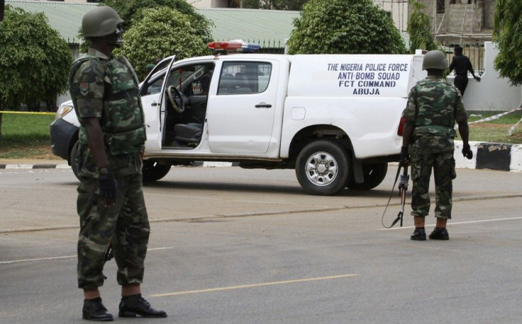 Soldiers take up positions near the scene of an explosion at a police station in Abuja
