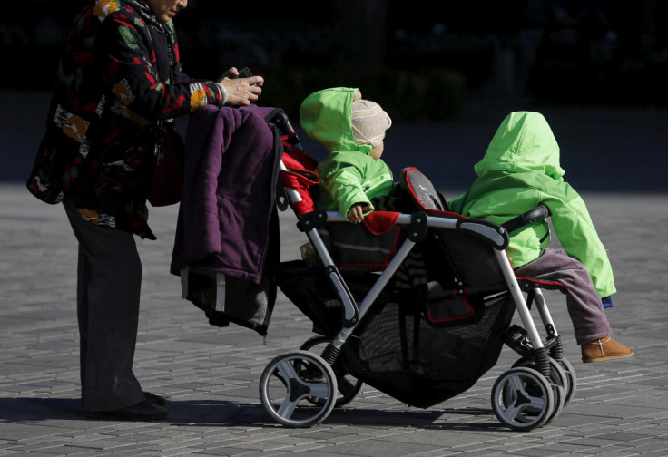 An elderly woman pushes two babies in a stroller in Beijing