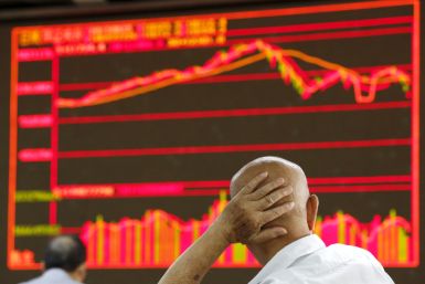 An investor looks at an electronic board showing stock information at a brokerage house in Beijing