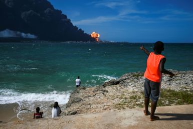 Cubans watch from a distance as a massive fire blazes at the fuel depot in Matanzas, Cuba