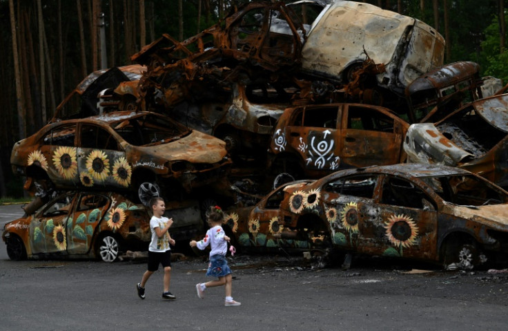 Children play near burnt-out cars -- some decorated by artists -- in Ukraine's Irpin near the capital