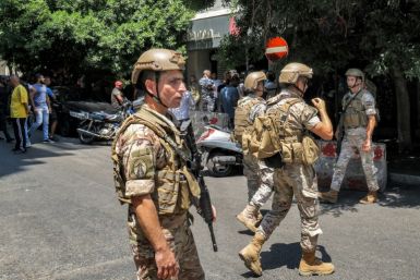 Lebanese army soldiers (front) and security forces (behind) gather outside a "Federal Bank" branch in Lebanon's capital Beirut where an armed customer was holding hostages