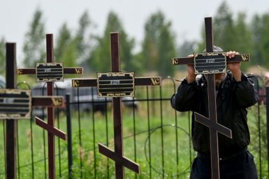 A municipal worker sets crosses with numbers on the graves of twelve unidentified civilians in the city of Bucha