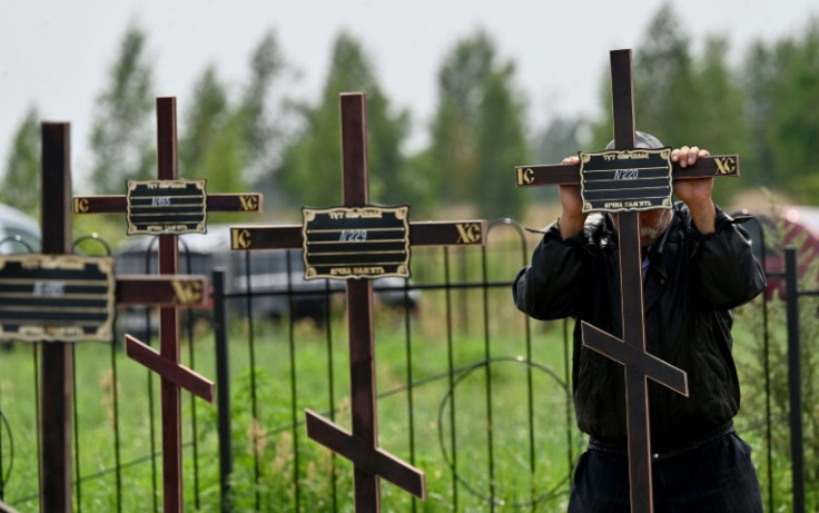 A municipal worker sets crosses with numbers on the graves of twelve unidentified civilians in the city of Bucha