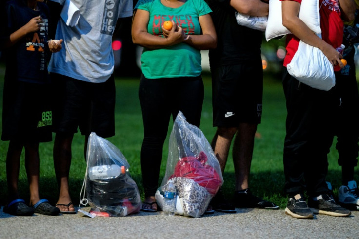 Migrants, who boarded a bus in Texas, listen to volunteers offering assistance after being dropped off within view of the US Capitol building in Washington, DC, on August 11, 2022