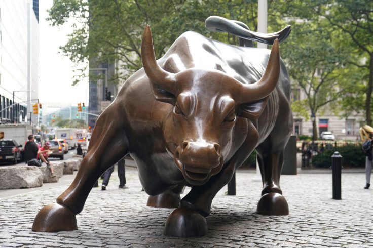 People pose for a photo at the Charging Bull statue, also known as the Wall St. Bull, is pictured in the financial district