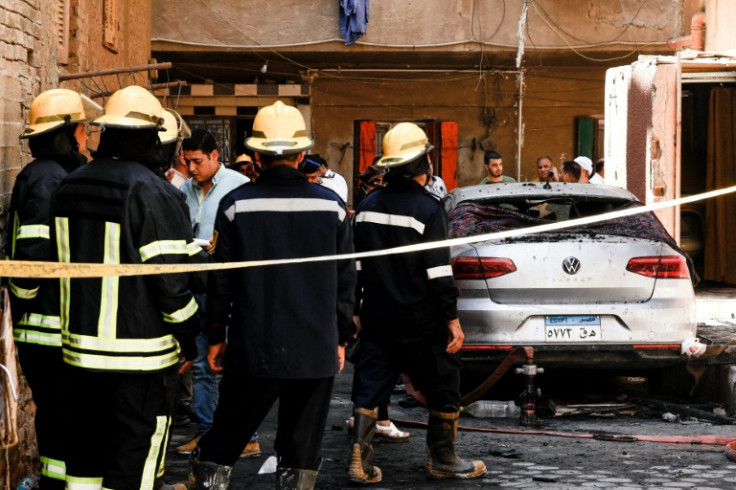 Firefighters stand outside the Abu Sifin church after more than 40 people were killed when a fire ripped through the building during Sunday mass