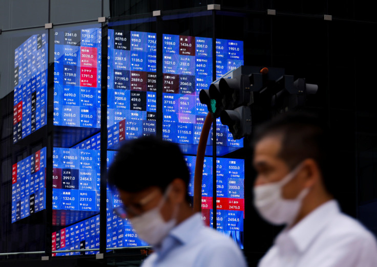 FILE PHOTO - People pass by an electronic screen showing Japan's Nikkei share price index inside a conference hall  in Tokyo