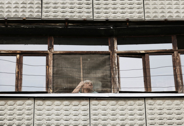 A woman looks out through the window of her house in Kramatorsk