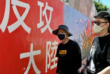 Tourists on Taiwan's Kinmen islands walk past a mural with a slogan that reads 'seize mainland China'
