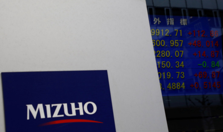Mizuho Financial Group's logo is seen next to an electronic board showing stock prices indexes at a branch of Mizuho Securities in Tokyo