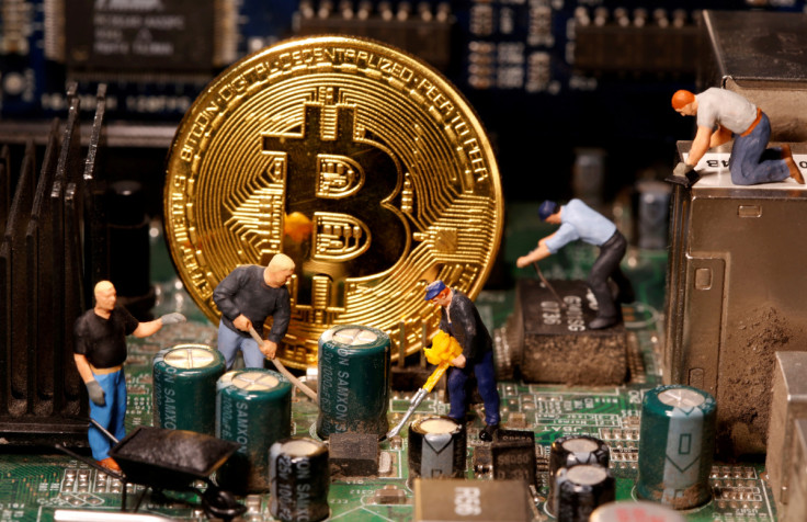 A representation of virtual currency Bitcoin and small toy figures are placed on computer motherboard