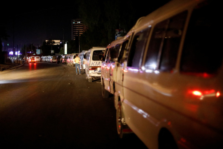 Public minibuses line up along a street in Damascus