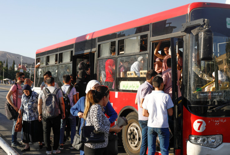 People board a packed public transportation bus, in Damascus