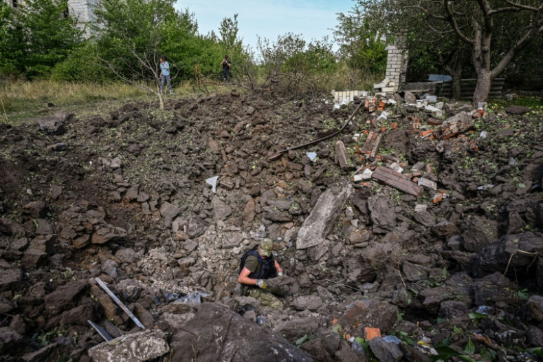 A Ukrainian deminer examines a crater following a missile strike in Rohan village near the city of Kharkiv on August 24, 2022, three days before Ukraine marks its anniversary of independence