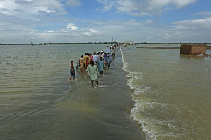 People walk along a flooded road to escape their villages in Punjab province