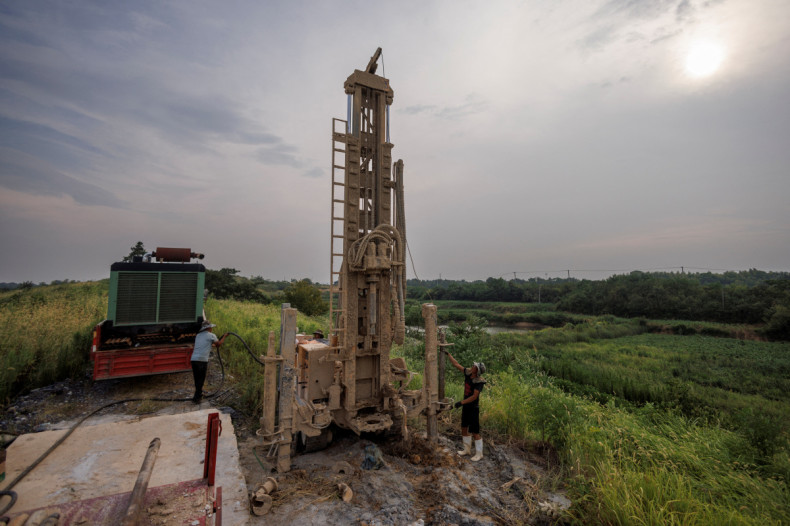 A drilling crew set up their machine to drill a well as the region experiences a drought outside Jiujiang city
