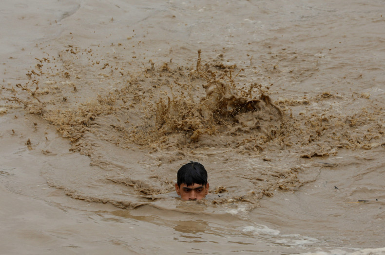 A man swims in flood waters while heading for a higher ground, following rains and floods during the monsoon season in Charsadda