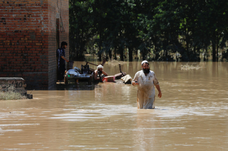 A man wades through flood waters trying to salvage his belongings following rains and floods during the monsoon season in Charsadda