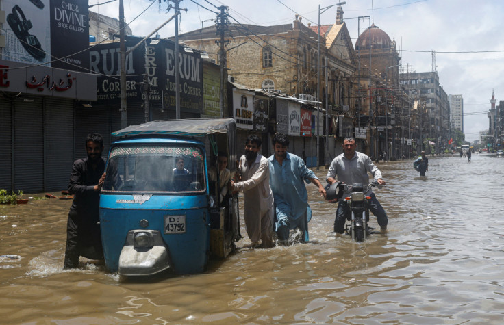 Residents commute through a flooded street during the monsoon season, in Karachi
