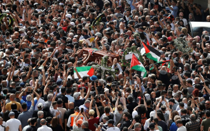 Para pelayat Palestina mengibarkan bendera nasional saat mereka membawa peti mati Shireen Abu Akleh selama prosesi pemakamannya di Yerusalem pada 13 Mei 2022.