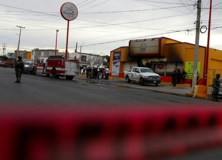 Soldiers, firefighters and forensic experts work at the site of an arson attack in the Mexican border city of Ciudad Juarez