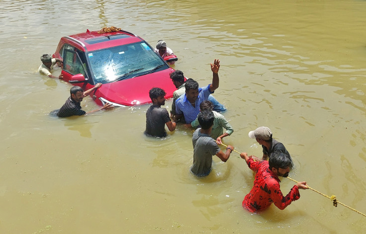 People pull a car through a water-logged road following torrential rains in Bengaluru