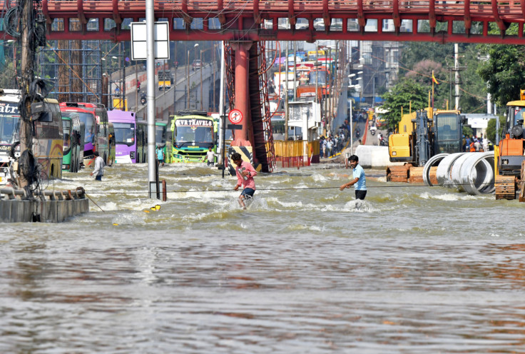 People use a cable to cross a waterlogged road following torrential rains in Bengaluru