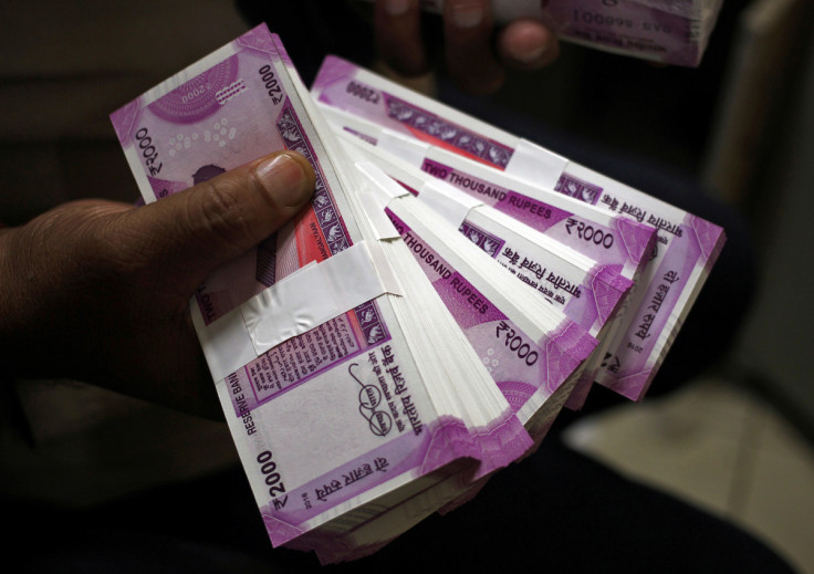 A cashier displays the new 2000 Indian rupee banknotes inside a bank in Jammu