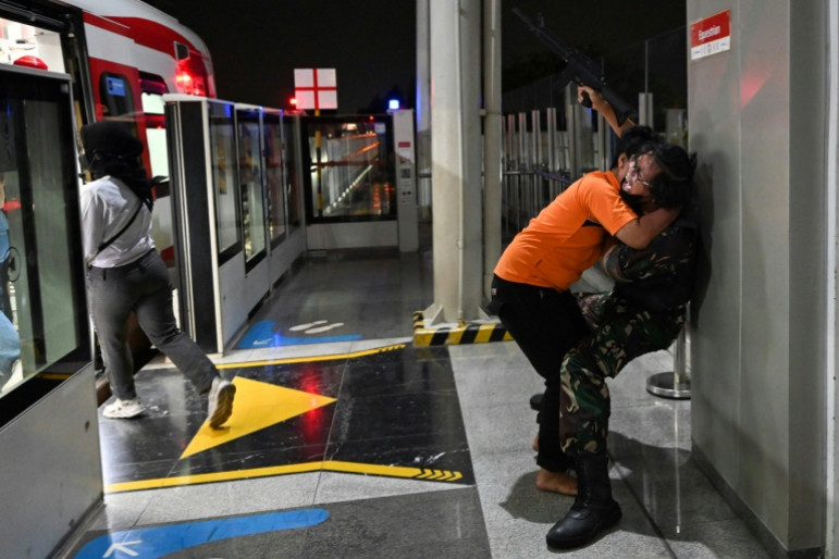 Soldiers armed with fake rifles fight the 'zombies' and try to escort passengers to safety