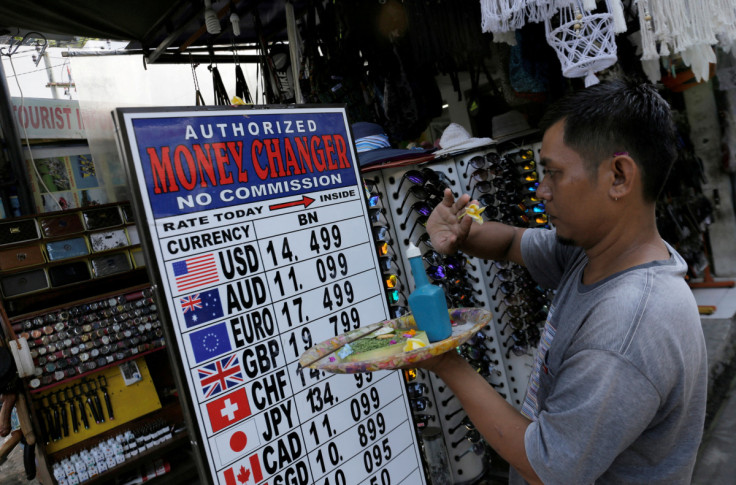 A Balinese man makes a Hindu offering outside a shop which offers currency exchange service in Kuta, on the resort island of Bali