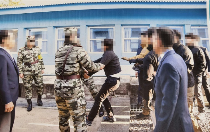 One of two alleged North Korean mass murderers (C, in black) appears to resist as authorities try to hand him over to Pyongyang officials in 2019