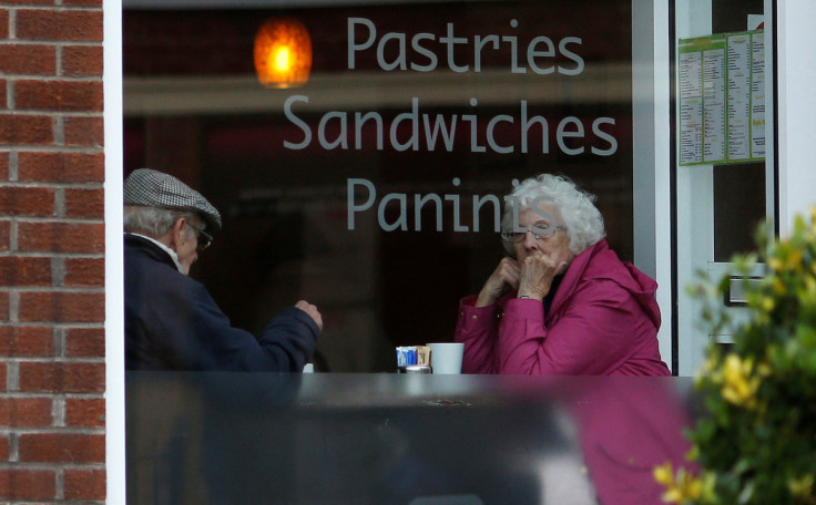 An elderly couple sit inside a coffee shop