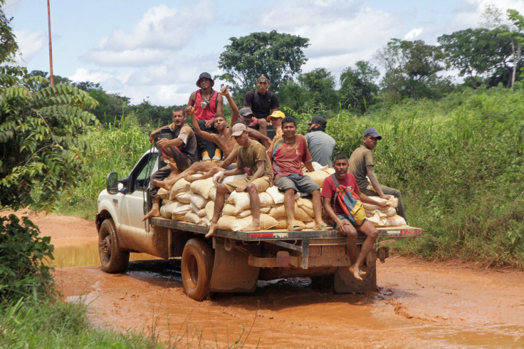 Workers sit on bags with gold-bearing sand, in El Callao