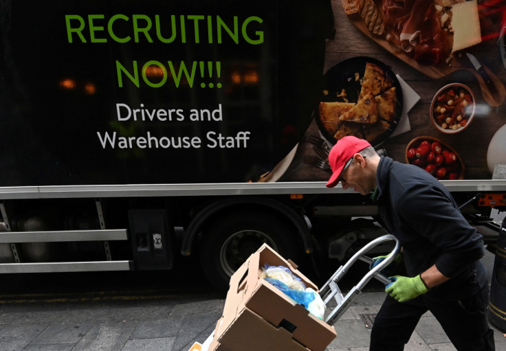 Lorry driver passes a sign on the side of his vehicle advertising for jobs as he makes a delivery, in London