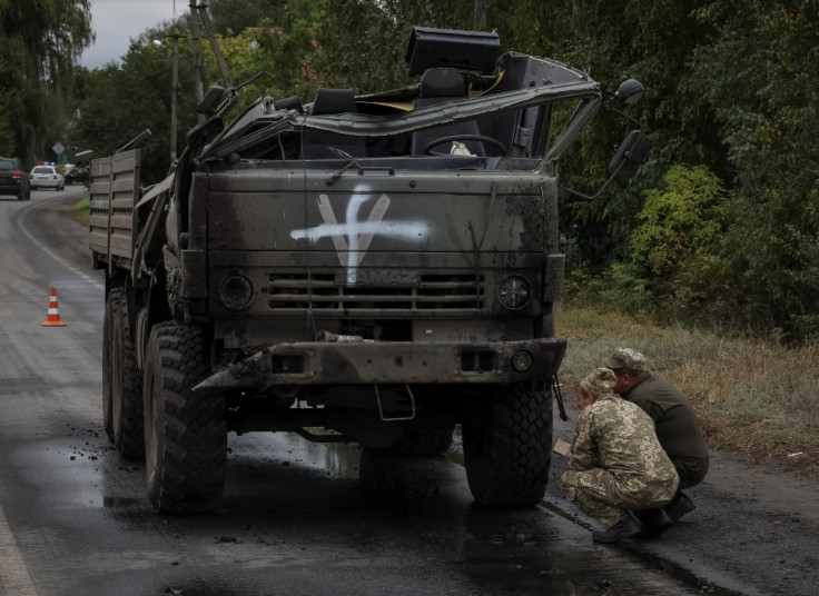 Ukrainian servicemen inspect a destroyed Russian military vehicle in Kharkiv region