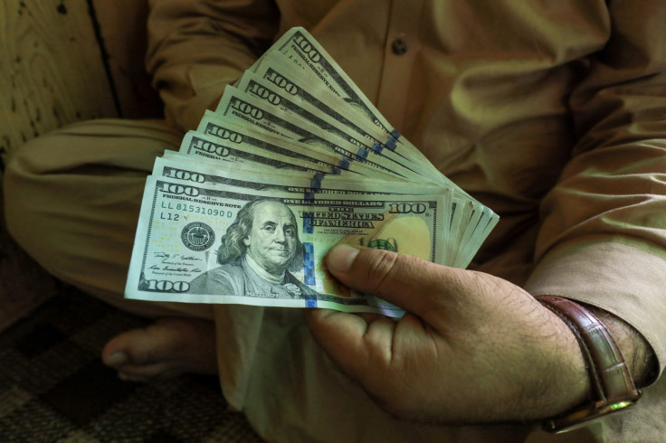 A trader displays U.S. dollar banknotes at a currency exchange booth in Peshawar
