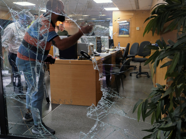Men are seen through a shattered window of a Blom Bank branch in Beirut