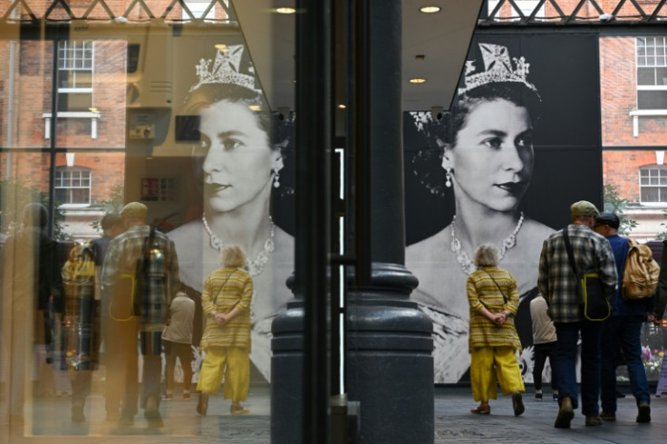 People walk past a giant portrait of Britain's Queen Elizabeth II in Spitafields Market in London, on September 16, 2022