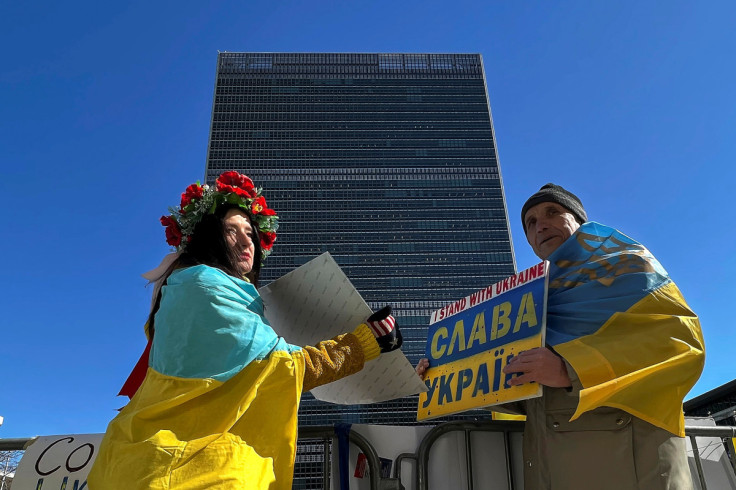 People showing support for Ukraine hold signs across the street from the UN headquarters building in New York City
