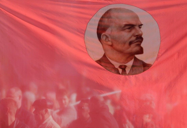Russian communist supporters are seen through a flag, displaying an image of Soviet state founder Vladimir Lenin, during a rally to mark the anniversary of the 1917 Bolshevik revolution in Stavropol