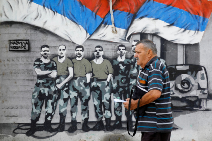 Man walks past a mural in North Mitrovica