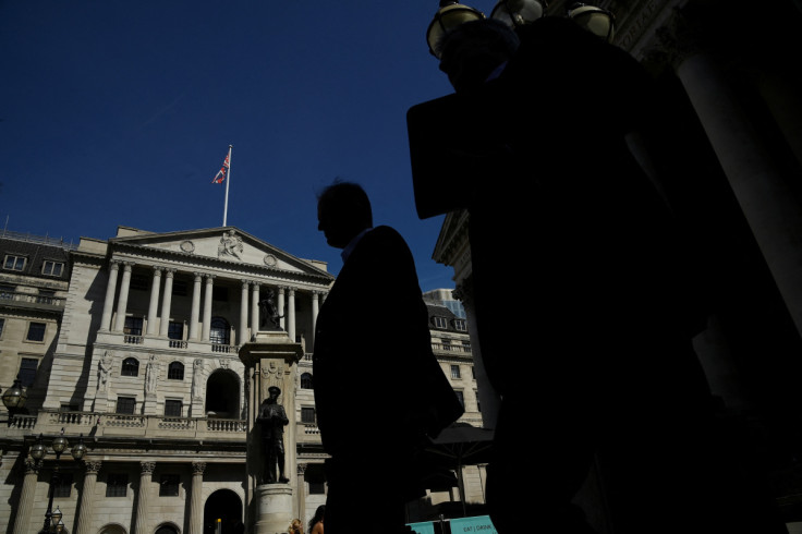 Workers are silhouetted as they walk past the Bank of England, in London