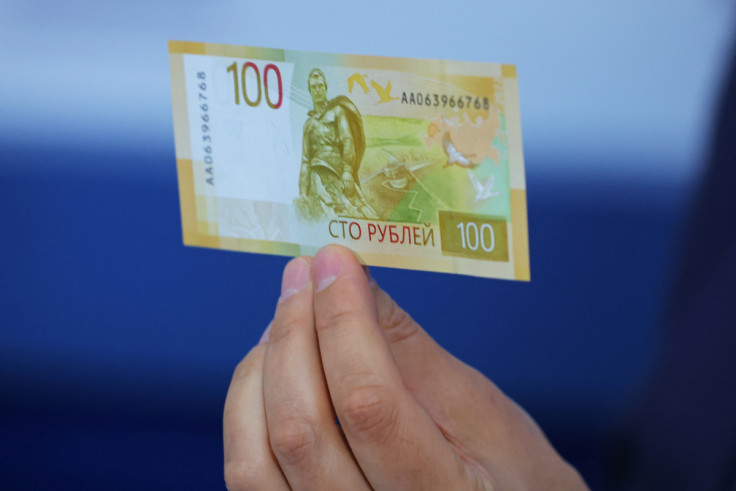 Deputy Governor of the Bank of Russia Sergey Belov holds the newly designed Russian 100-rouble banknote during a presentation in Moscow