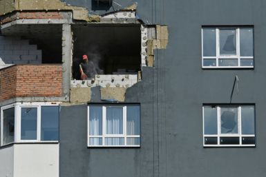 A construction worker sweeps dust from a damaged flat during repair work at an apartment block destroyed by shelling in Irpin