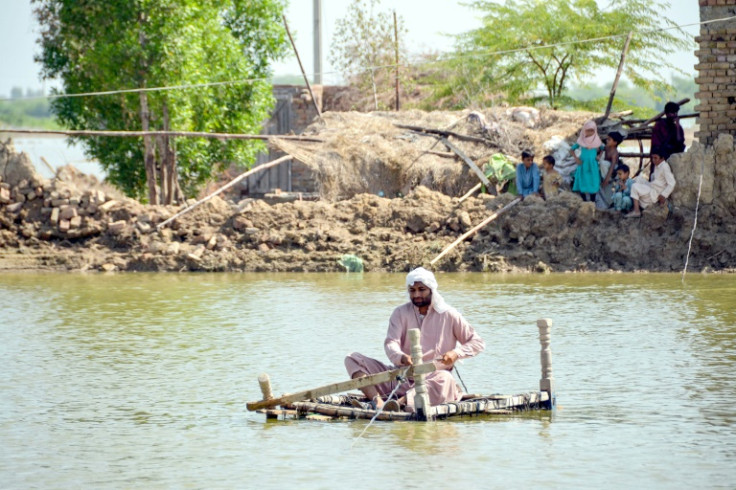A man uses a makeshift raft to cross s stream of flood waters near his damaged house in Jaffarabad, Pakistan