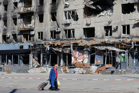 A local resident walks past a damaged apartment block in Mariupol