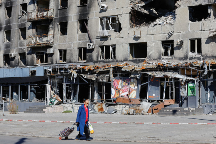 A local resident walks past a damaged apartment block in Mariupol