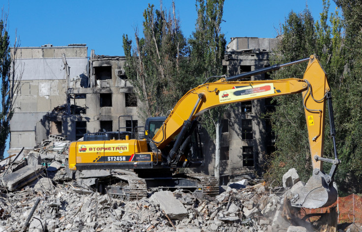 An excavator removes debris of a destroyed apartment block in Mariupol