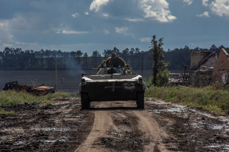 Ukrainian service members ride atop an armoured fighting vehicle in Kharkiv region